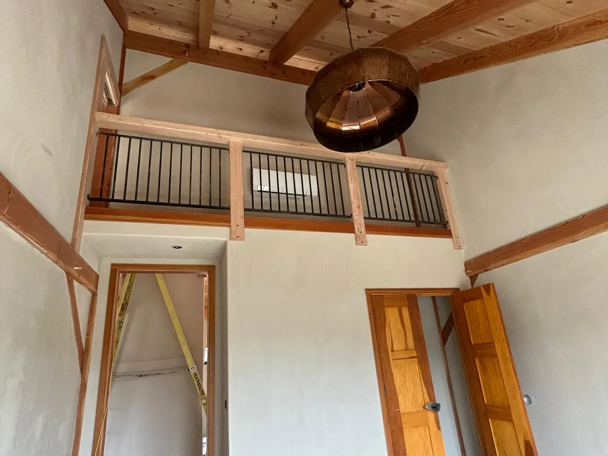 American Clay walls in a timber frame home with an interior balcony and a copper pendant