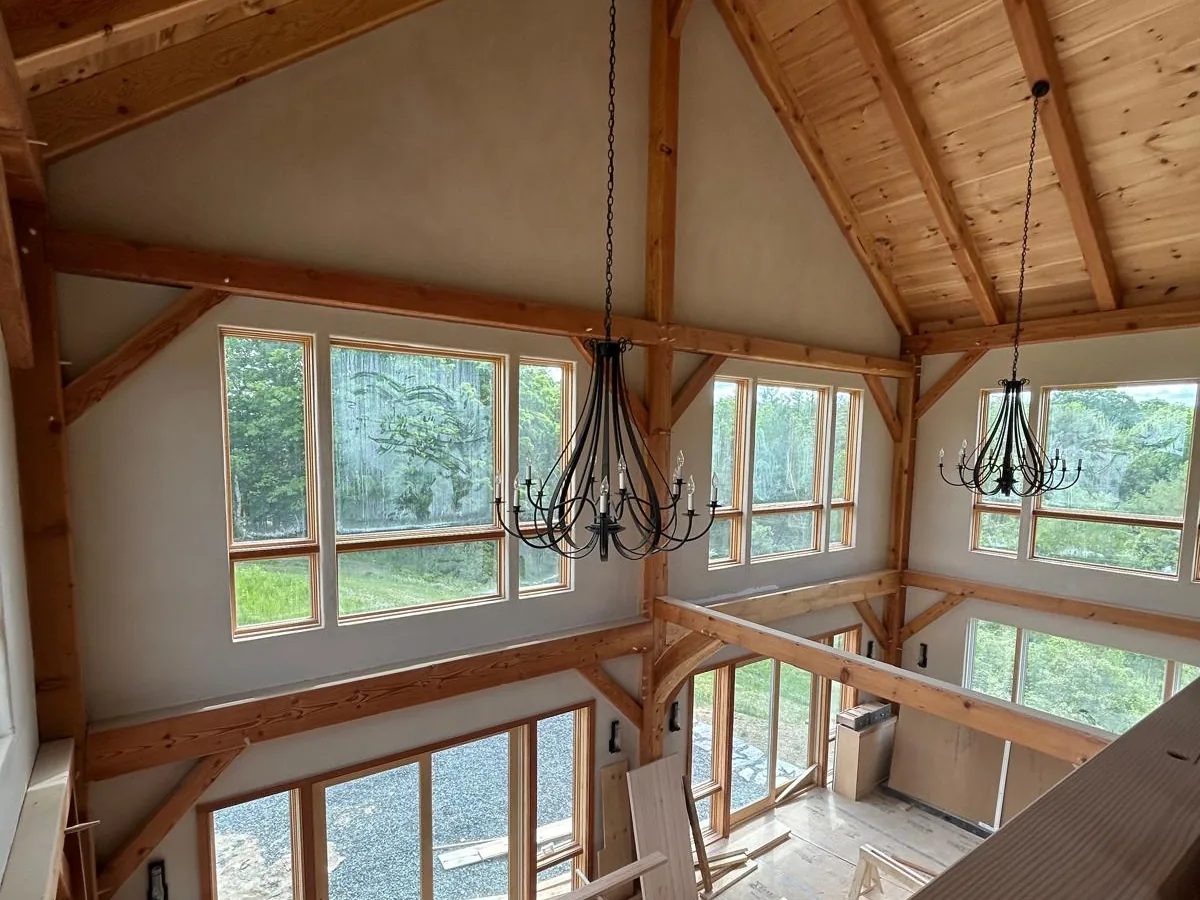 American Clay walls in a timber frame great room with a chandelier and a wall of windows