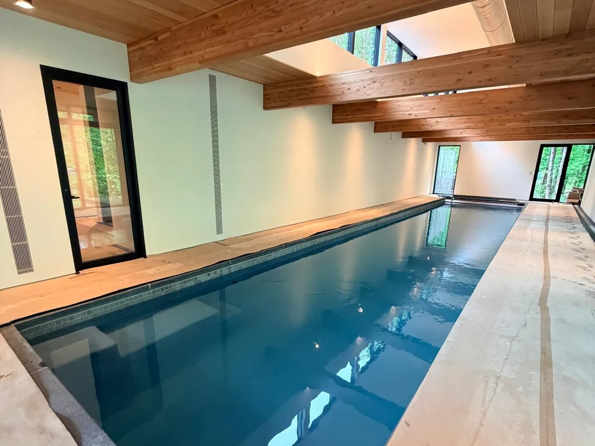 Indoor lap pool hall with plastered walls under a timber ceiling