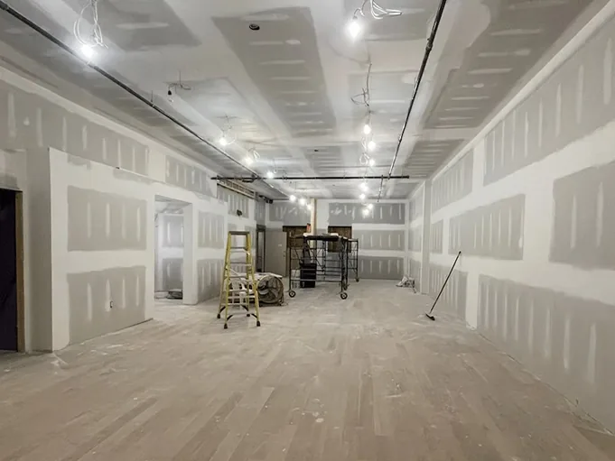 Large commercial space with drywall walls and ceiling taped and coated, ready for sanding