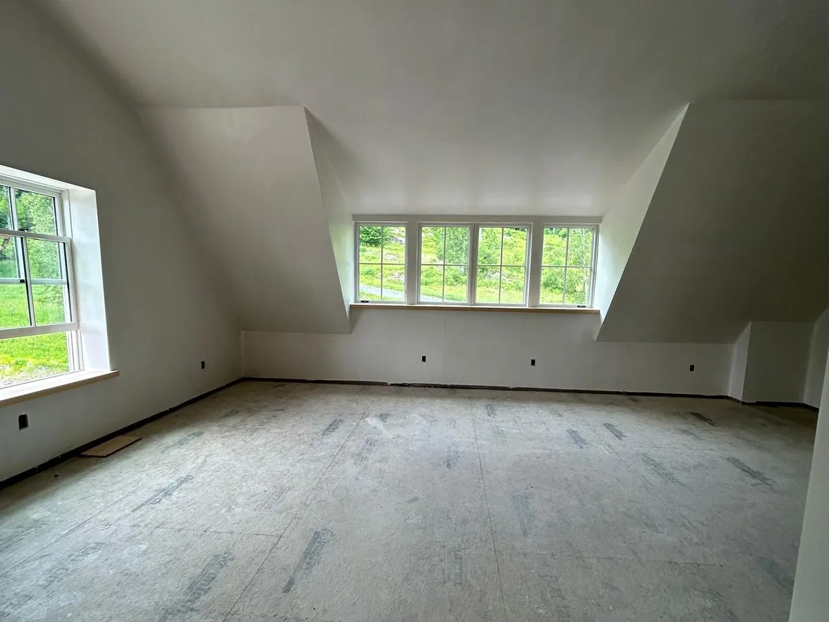 Finished drywall in a dormer bedroom with a bank of windows