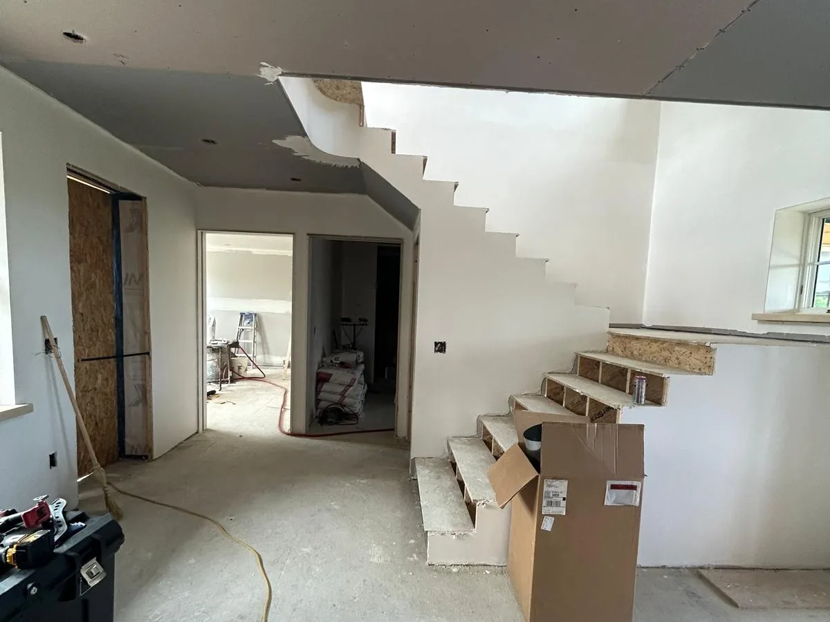Drywall finished around a staircase and its stepped stringer wall