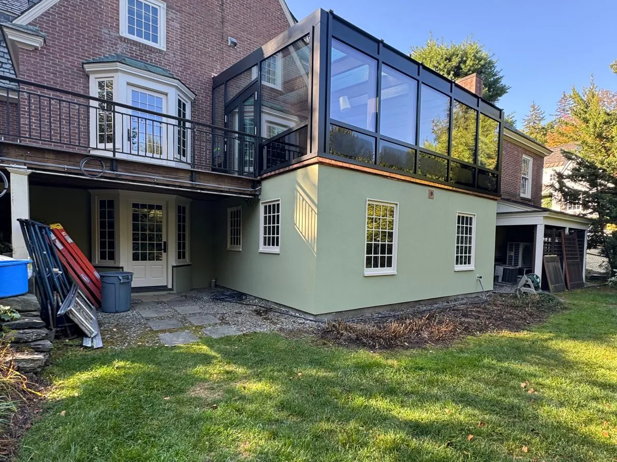 Finished exterior of a house with a painted lower level and a modern glass addition above