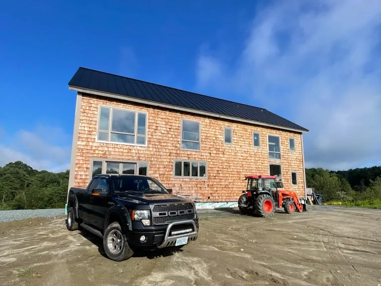 Shingled house with the exterior finished, truck parked on the drive