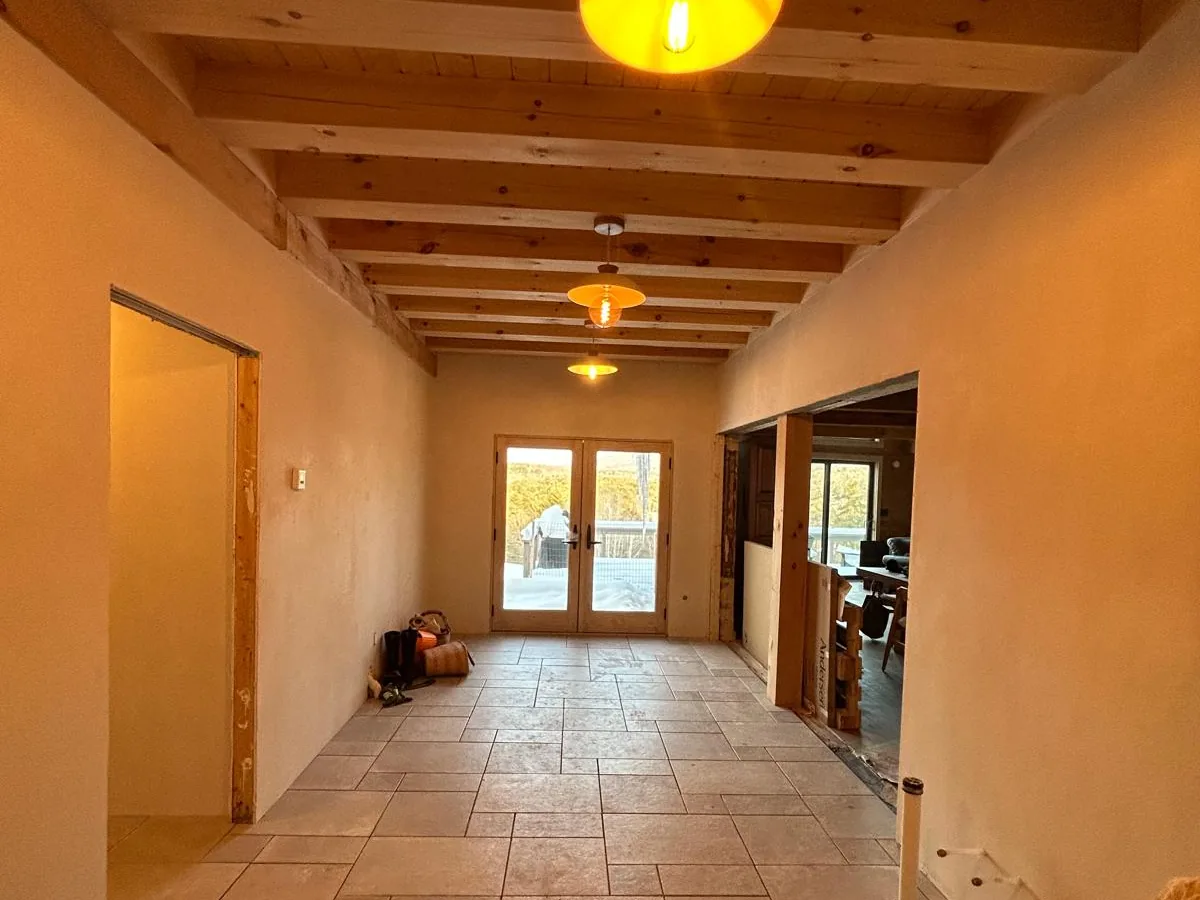 Plastered corridor over a terracotta tile floor with timber beams overhead
