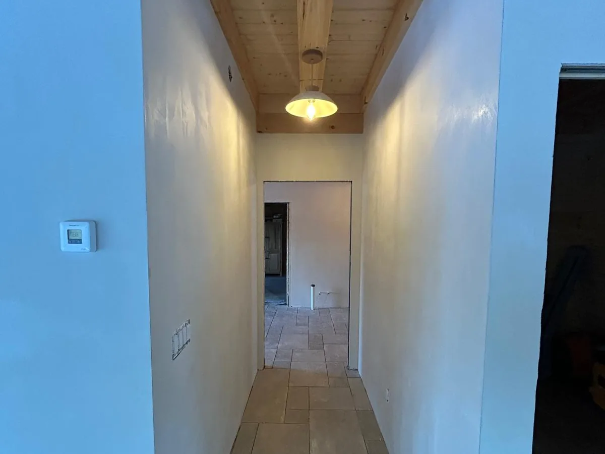 Warm plastered corridor with a pendant light and a tile floor