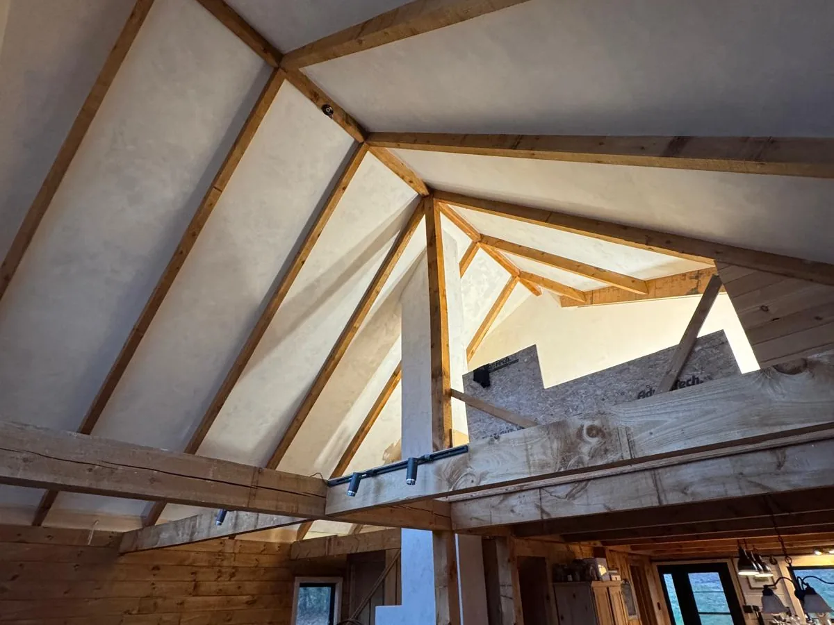 Plastered cathedral ceiling between timber rafters in a finished great room