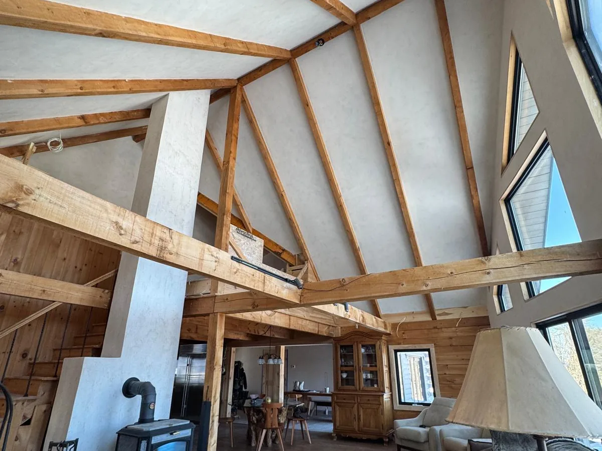 Great room with plastered walls, exposed timber and a wood stove