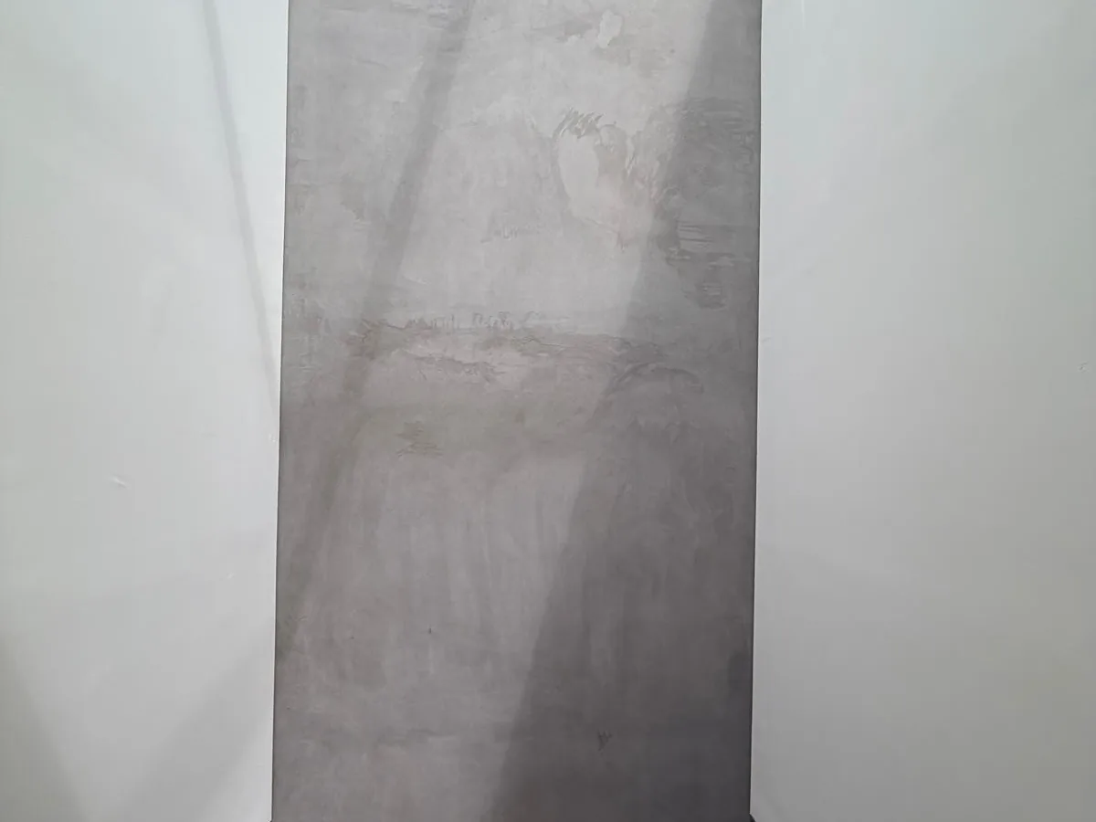 Tall grey microcement feature panel rising two storeys in a modern stairwell