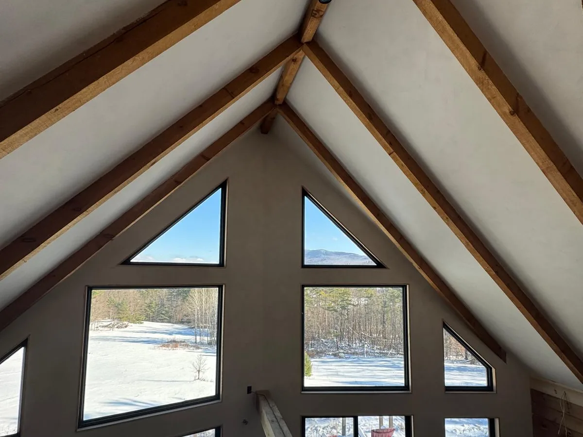 Plastered gable wall framing a peak of windows in a timber frame home