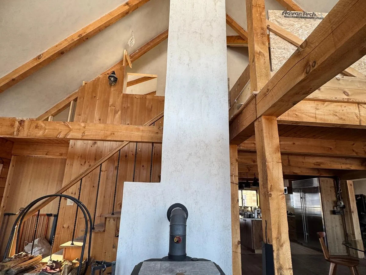Plastered chimney column with a wood stove in a lived in timber frame house