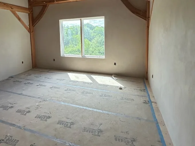 Freshly plastered walls around a large window in a timber frame room