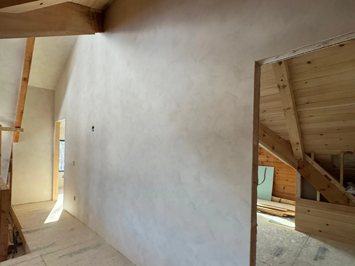 Plastered attic room with a sloped ceiling and daylight from the gable