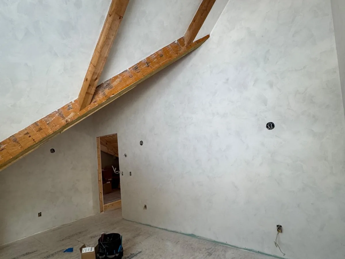 Plaster finished walls between exposed timber trusses in an upper room