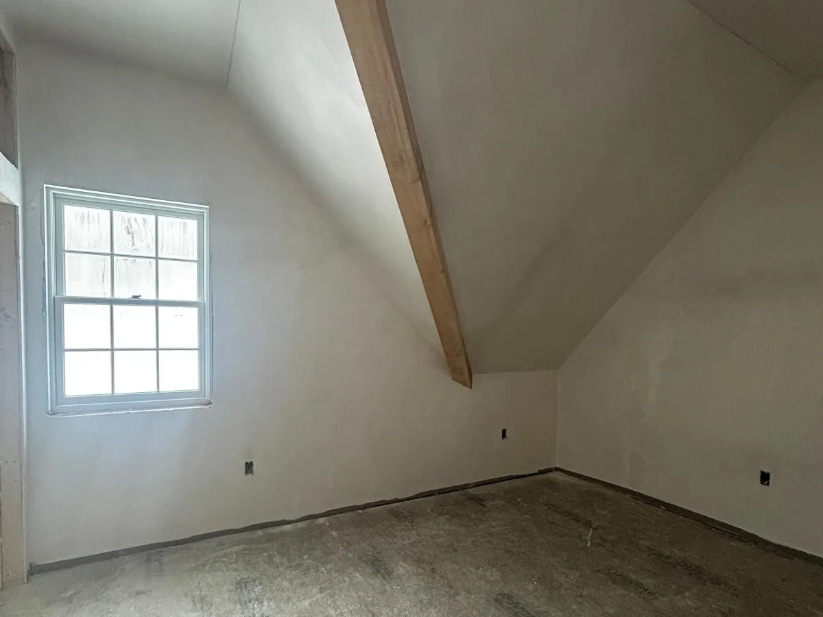 Plastered bedroom with a sloped ceiling and a small dormer window