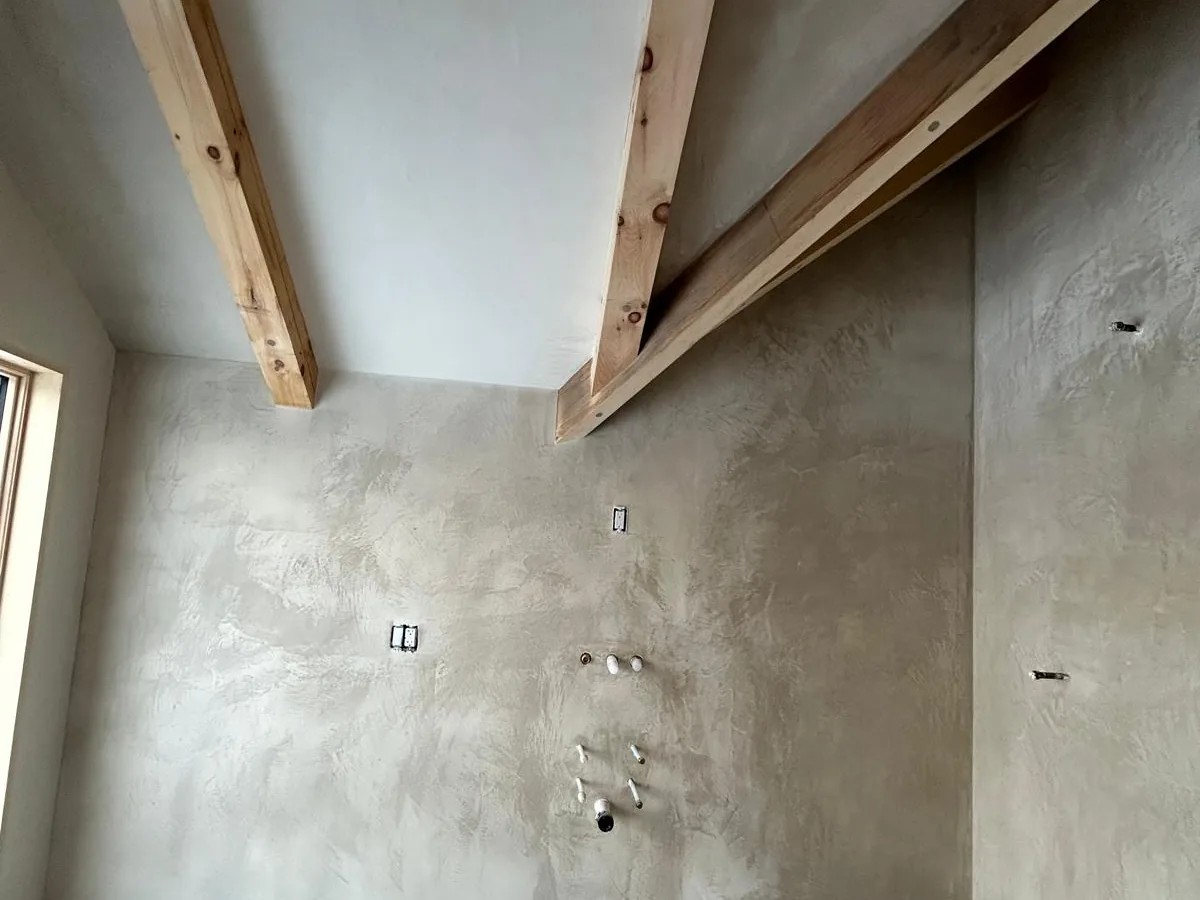 Plastered walls and ceiling between exposed beams in a finished upper room