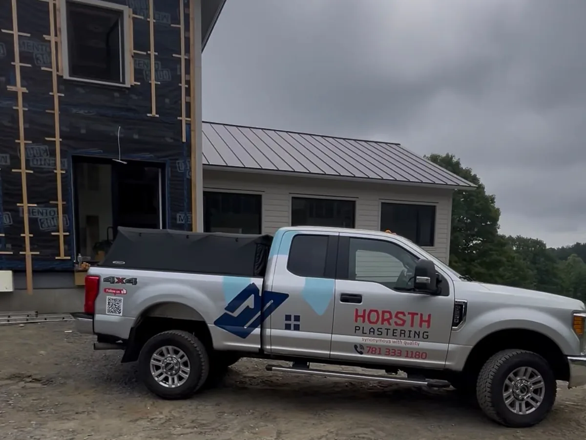 White Horsth Plastering pickup truck parked at a job site in front of a house under construction