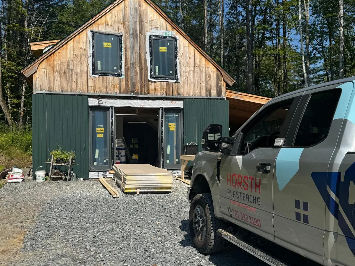 Horsth Plastering truck parked outside a timber barn project on a gravel drive
