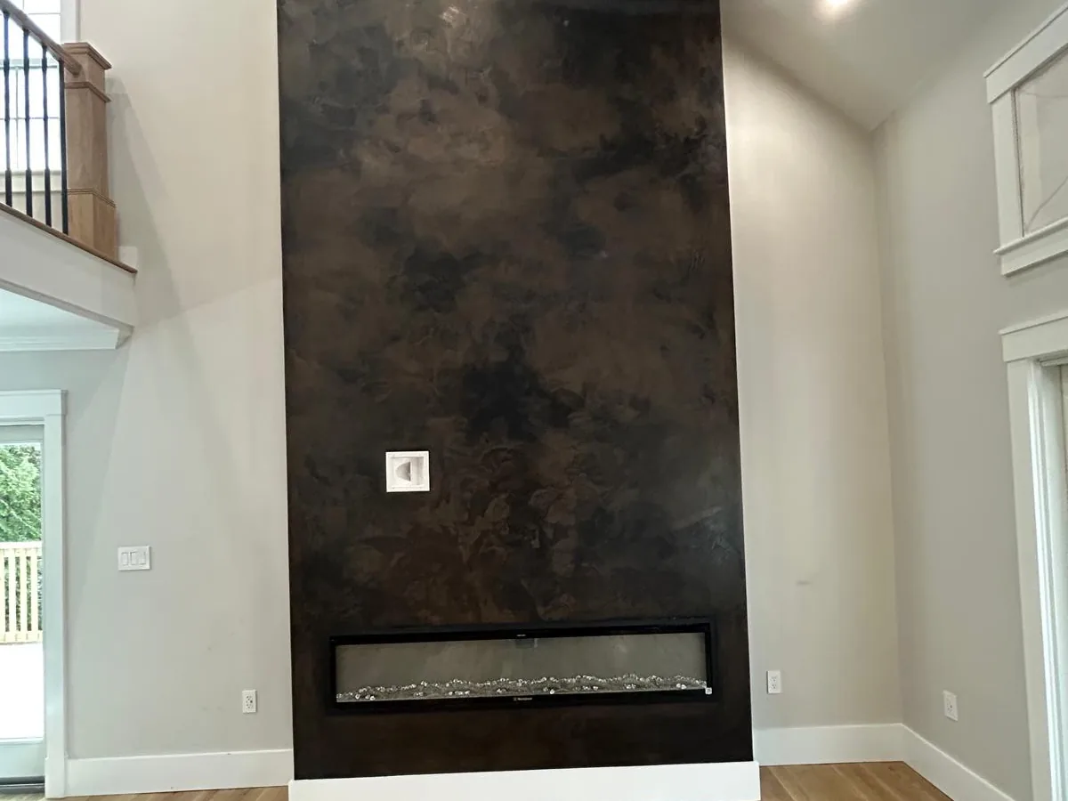 Bronze toned Venetian plaster chimney breast running floor to ceiling beside a staircase
