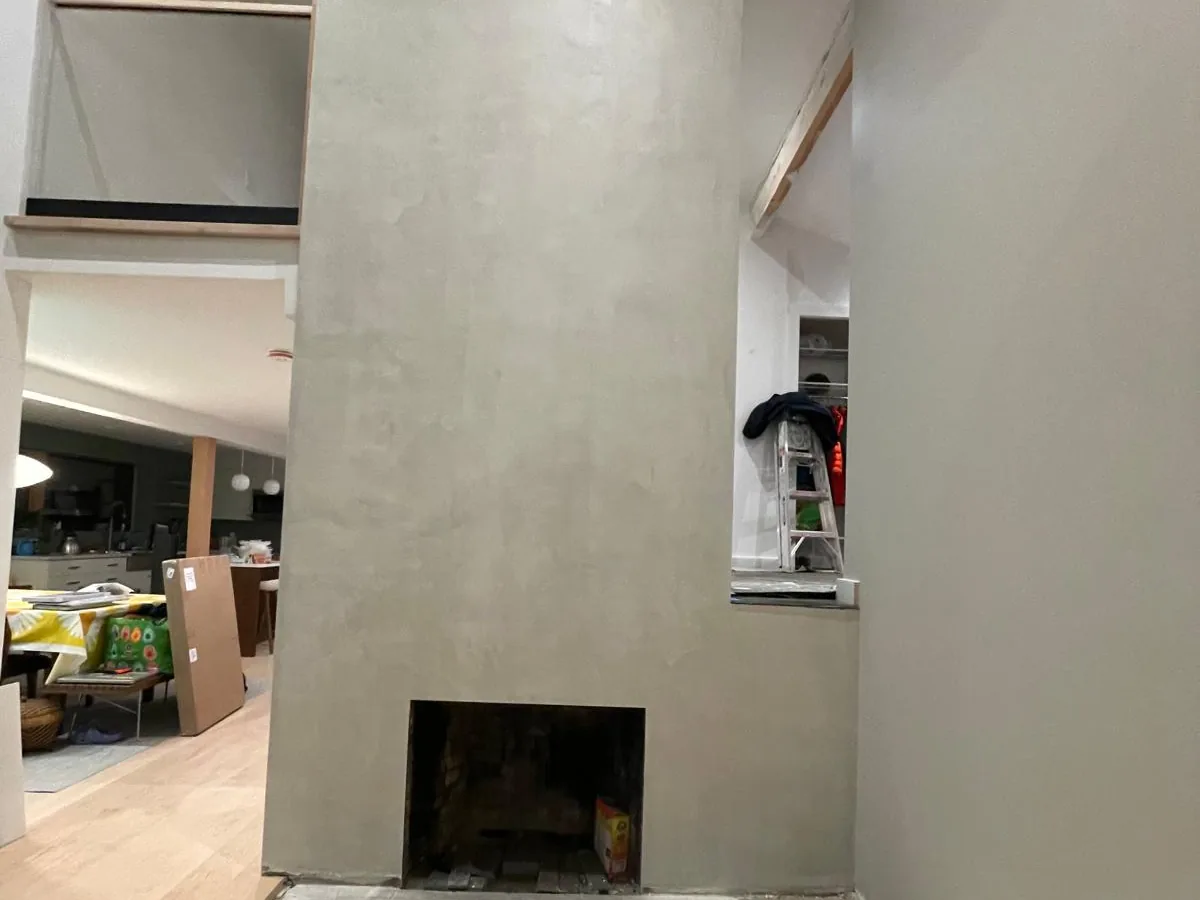 Polished grey plaster fireplace in an open living space with white oak flooring
